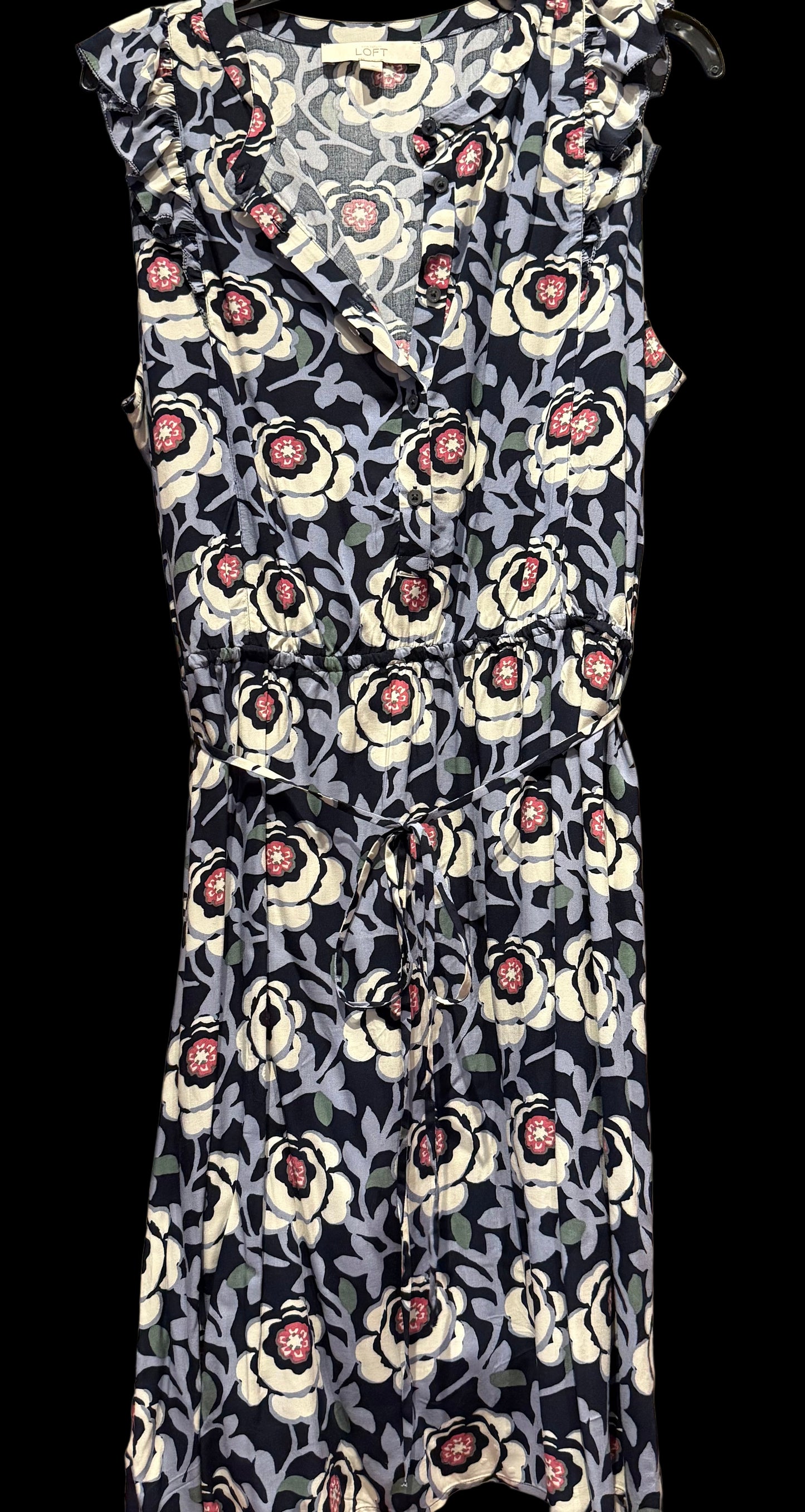 Floral dress with black, white, and pink pattern on a wooden rack.