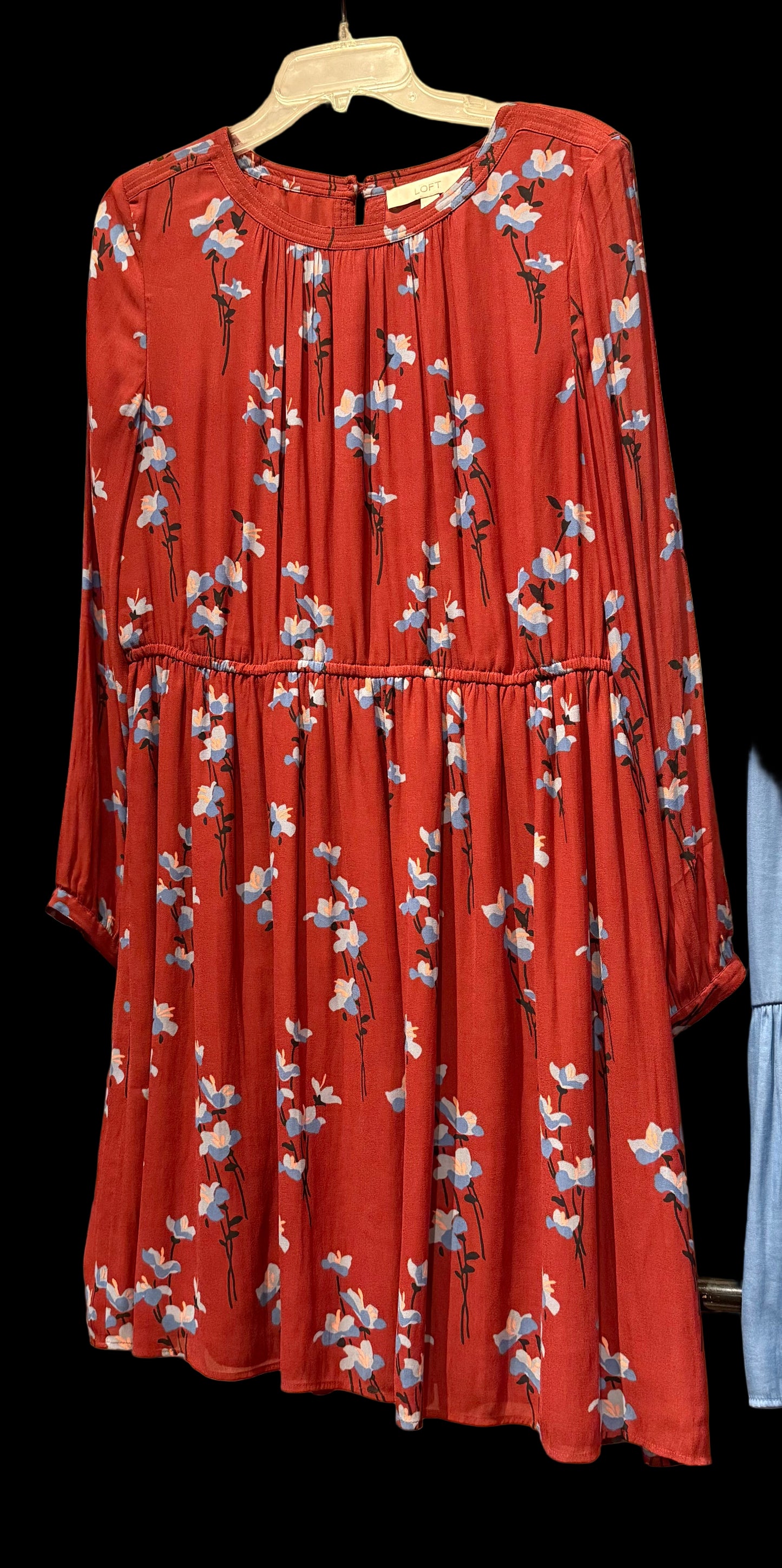 Red floral dress hanging against a brick wall.