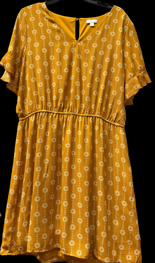 Yellow dress with a floral pattern on a hanger against a white wall.