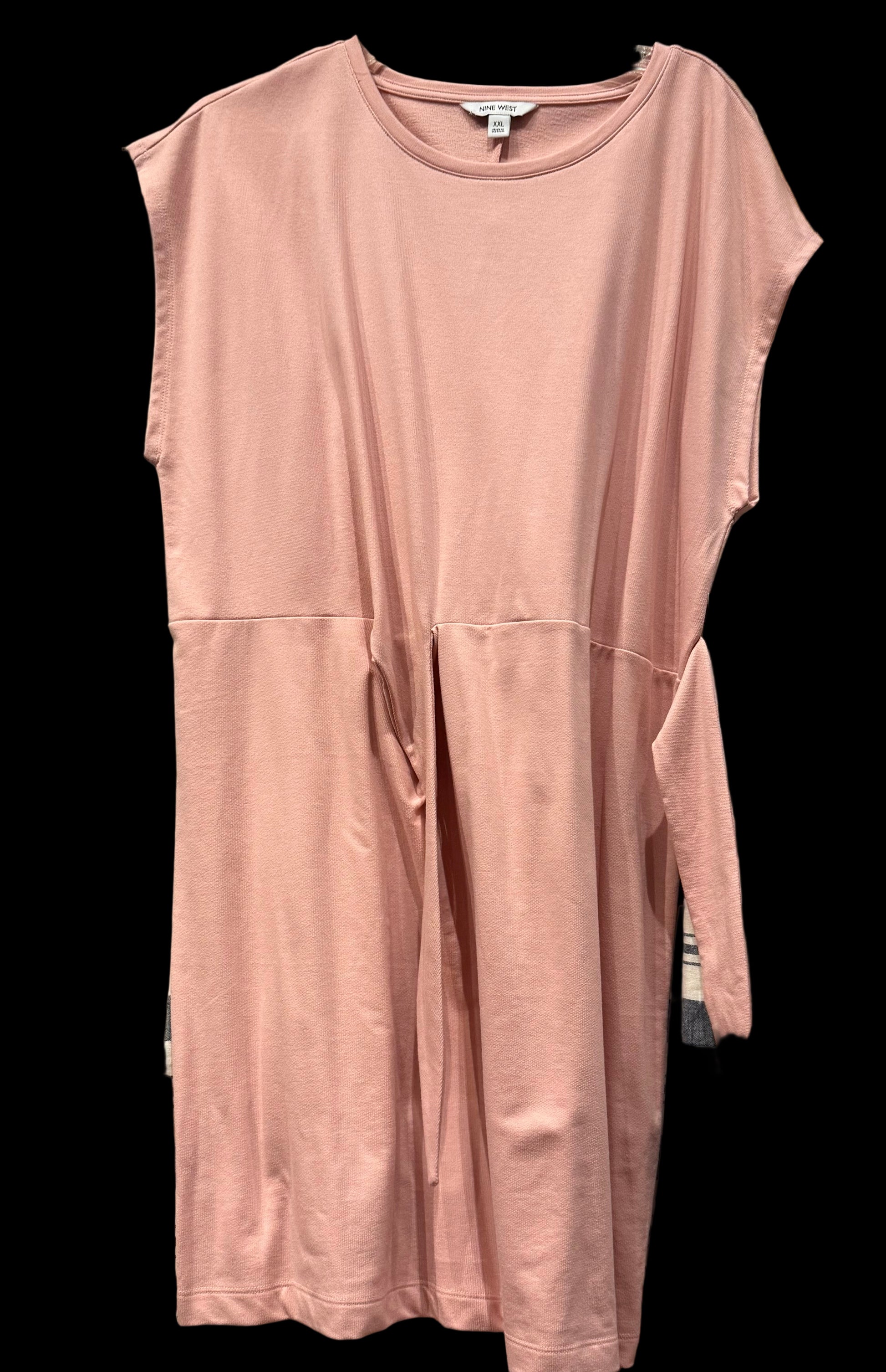 Pink sleeveless dress on a hanger against a wooden wall with other clothing items.
